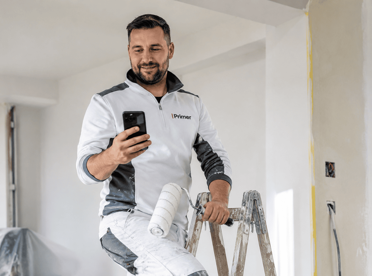 Vakman op een trap bekijkt zijn offerteaanvraag op zijn telefoon
